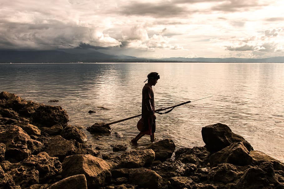 Person Holding Spear Beside Body of Water, beach, calm, clouds HD wallpaper