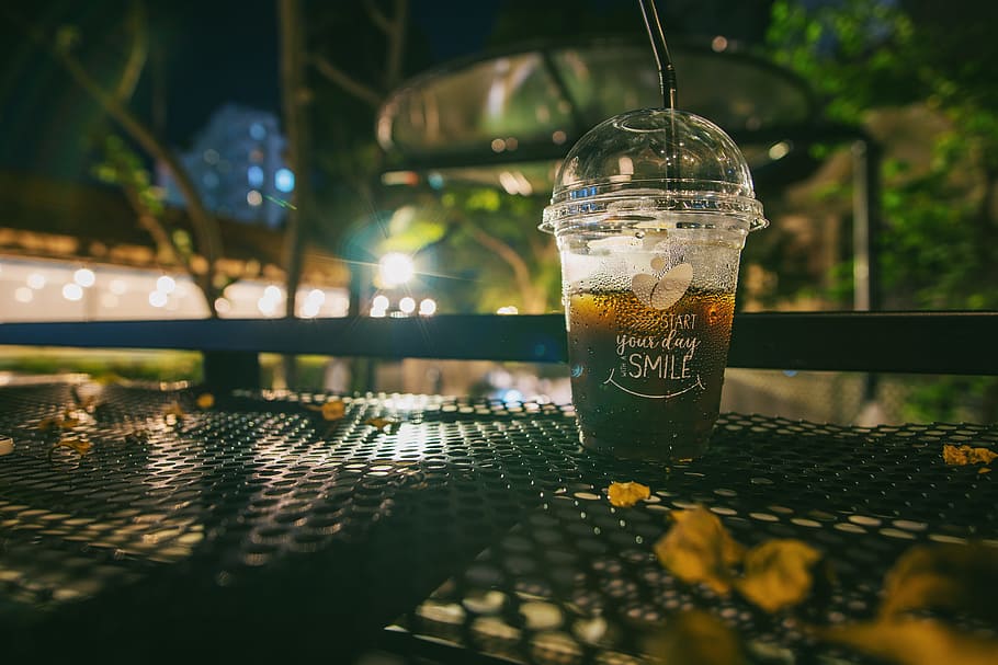 Clear Plastic Disposable Cup With Straw Half-filled With Juice on Metal Table HD wallpaper