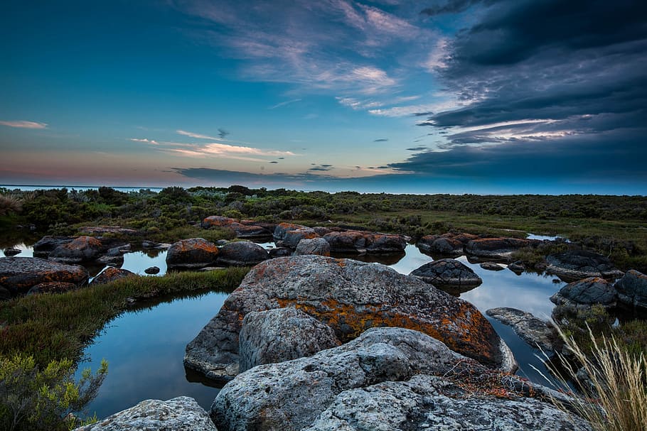 Tranquility at dusk, landscape photography of rock surrounded by body of water and green grass HD wallpaper