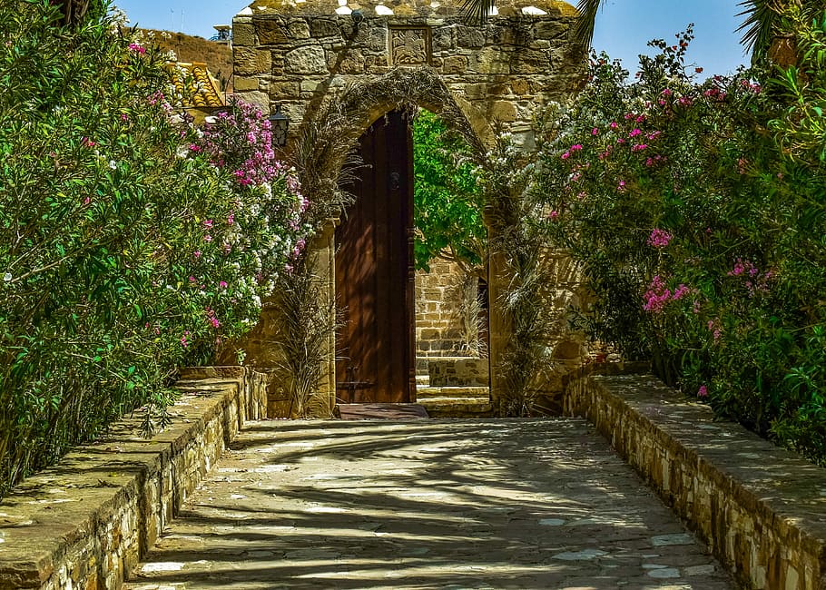 brown concrete arch gate surrounded by flowers, monastery, entrance