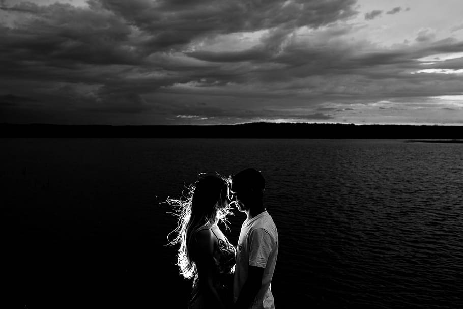 grayscale photo of man and woman kissing beside the body of water HD wallpaper