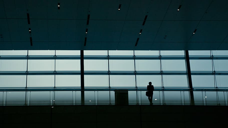 silhouette photograph of man standing while leaning on glass building barricade HD wallpaper