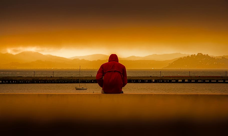 Person Wearing Red Hoodie Sitting In Front of Body of Water, alone HD wallpaper