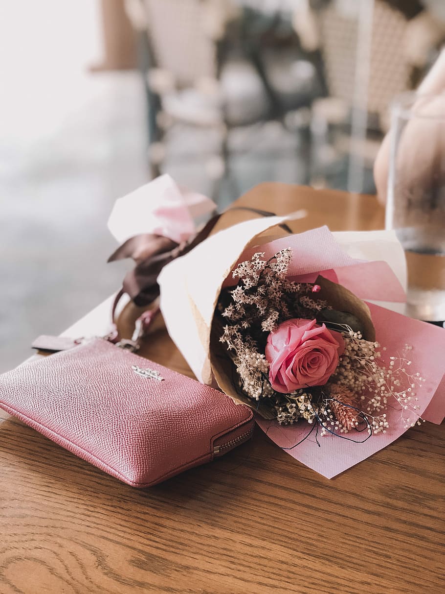 pink rose flower near the pink Coach leather wallet on brown wooden table, photo of bouquet of flowers beside pink Coach leather wristlet, HD wallpaper