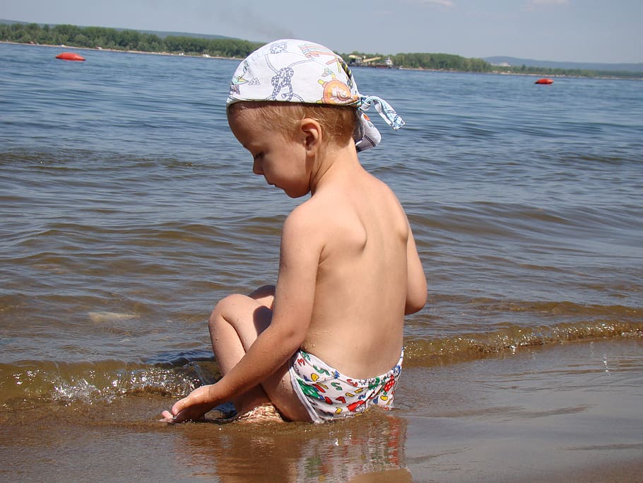 boy sitting on brown sand near the water at daytime, kid, beach HD wallpaper