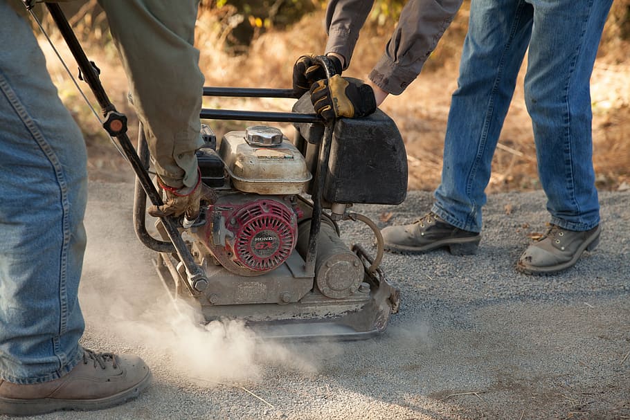 two people holding gas stamper during daytime, workers, trail builder HD wallpaper