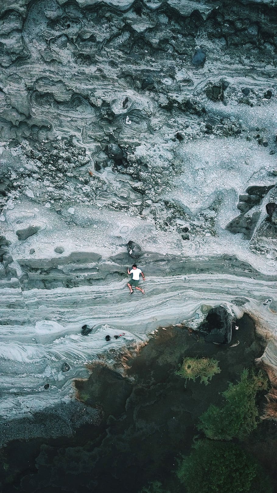 man laying on grey and white rock surface during daytime, aerial photography of man lying on ground HD wallpaper