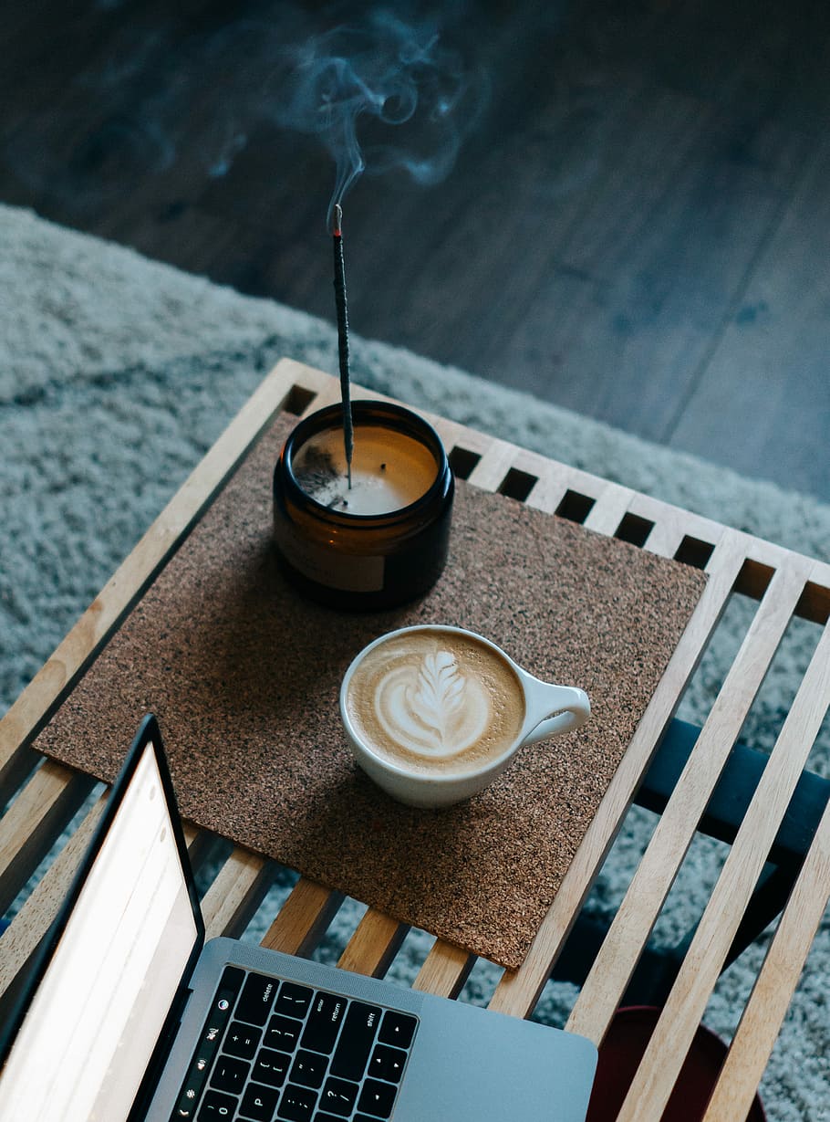 cappuccino in cup, cappuccino filled white cup beside brown jar with lit incense stick and MacBook Pro HD wallpaper