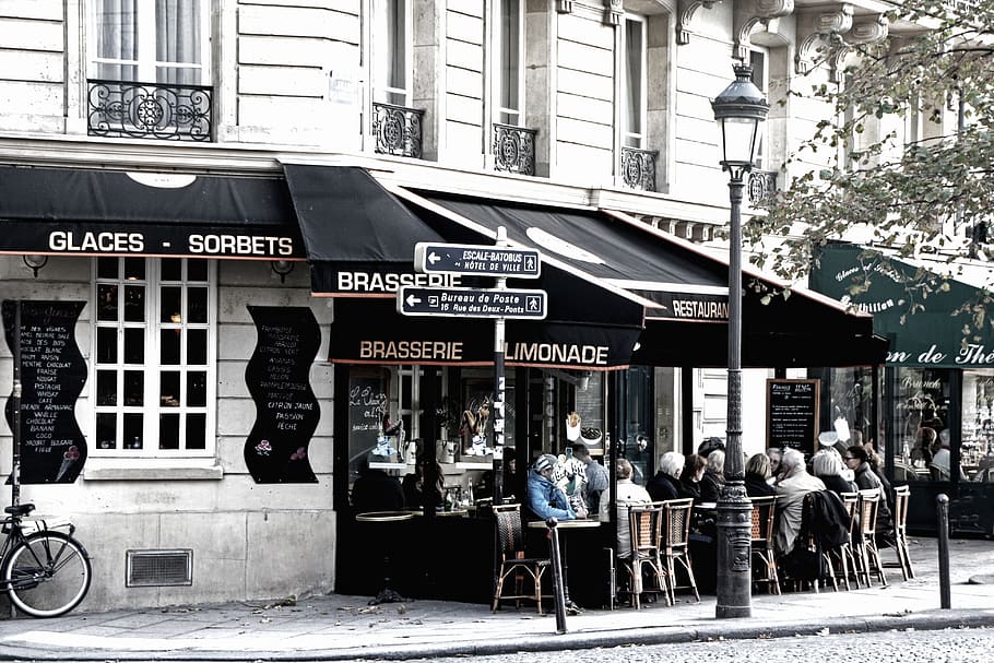 crowd of people sitting in front of store during daytime, paris