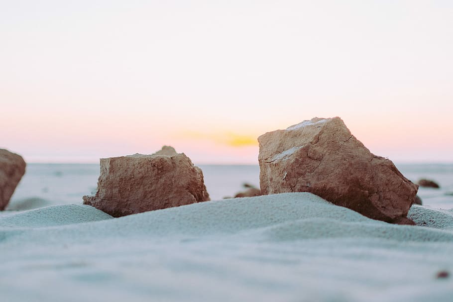 brown boulders on gray sand, brown stone on gray stand, beach HD wallpaper