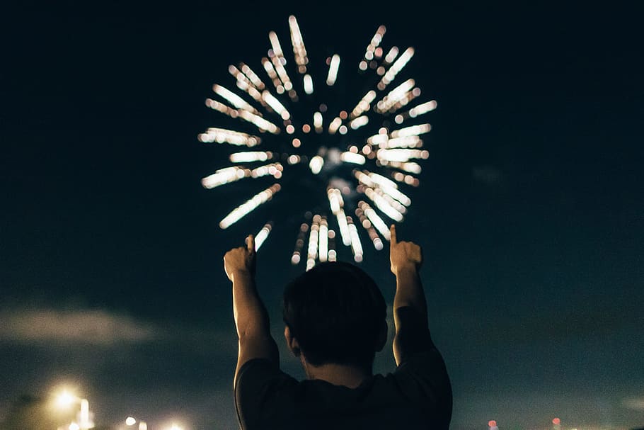 man in black shirt pointing towards brocade fireworks in the skies, man in black top watching fireworks HD wallpaper