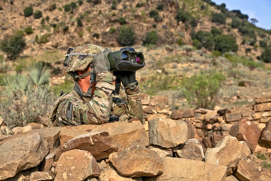 soldier behind rock using binocular, reconnoiter, scout, explore