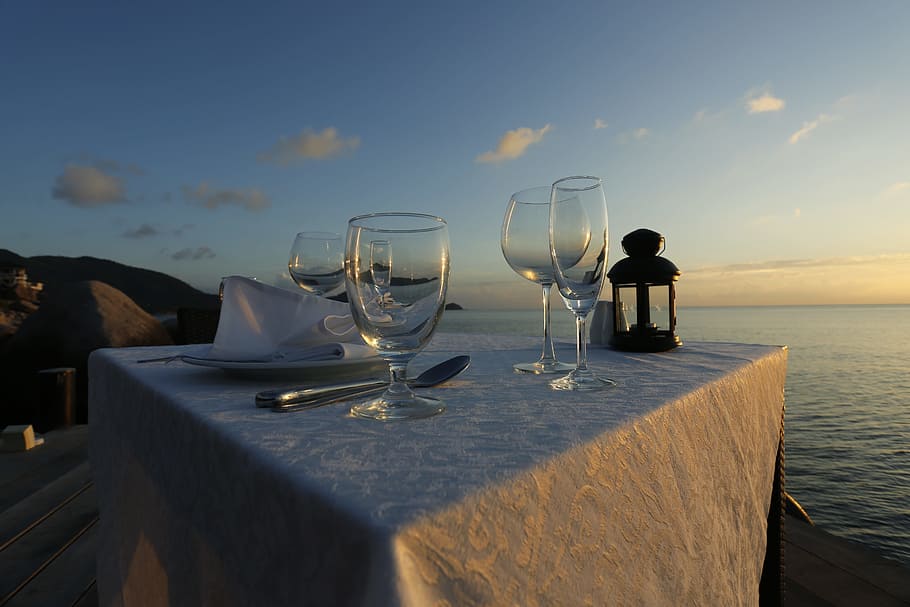 four empty wine glasses on white tablecloth near body of water at golden hour, HD wallpaper