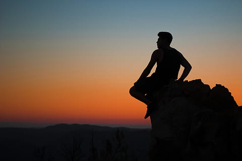silhouette of man sitting at rocks, man sitting on edge of stone HD wallpaper