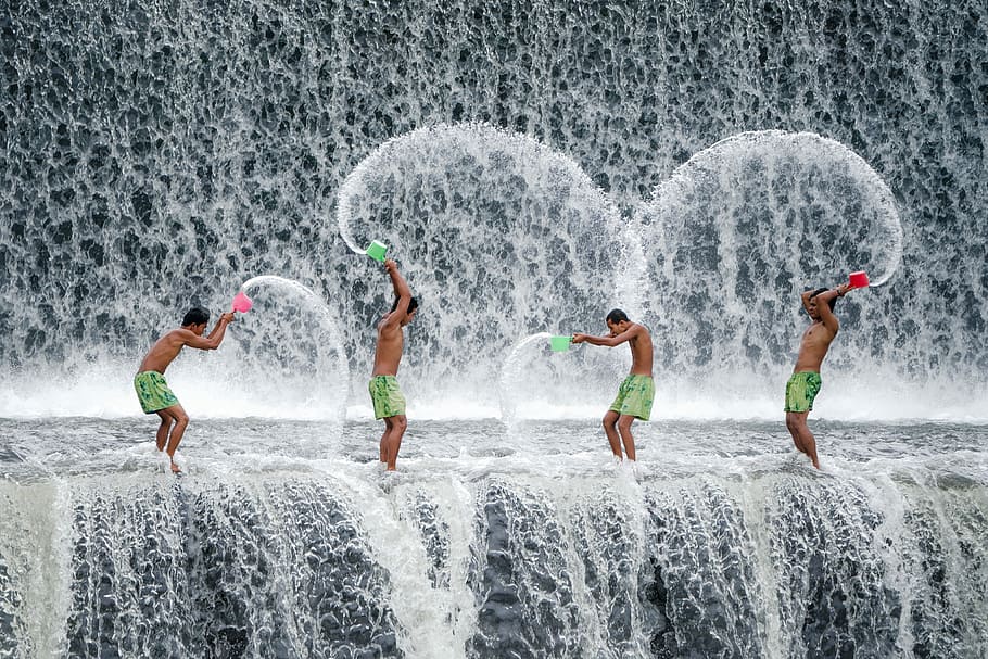 four men throwing dipper of water on waterfalls during daytime, four people playing at the waterfall HD wallpaper