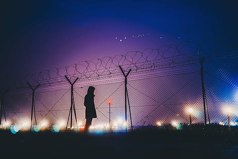 silhouette photograph of person standing beside link fence HD wallpaper