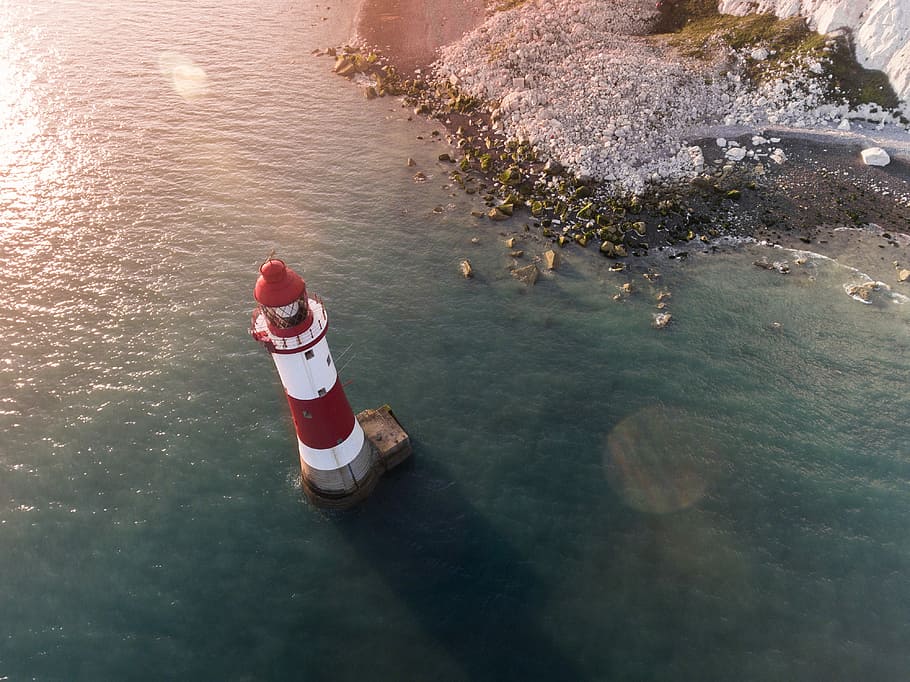 white and red lighthouse in body of water near shore, red and white lighthouse on a body of water HD wallpaper