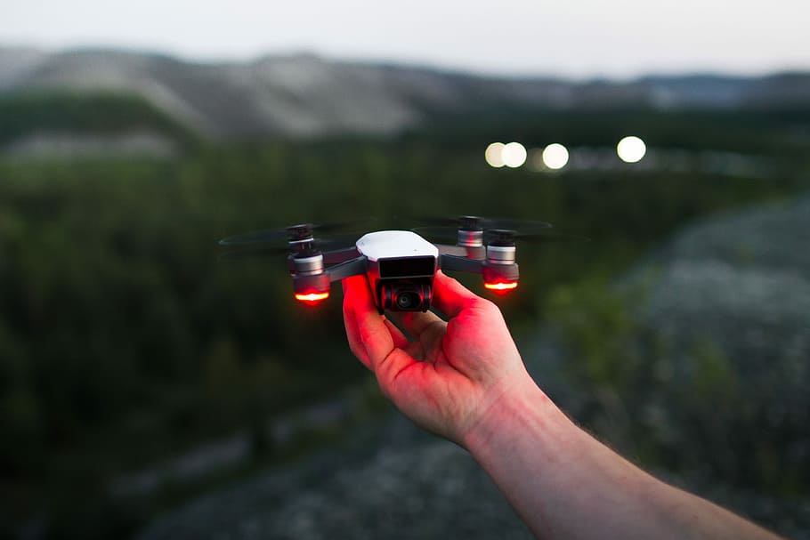 person holding black and red quadcopter, person holding white drone HD wallpaper