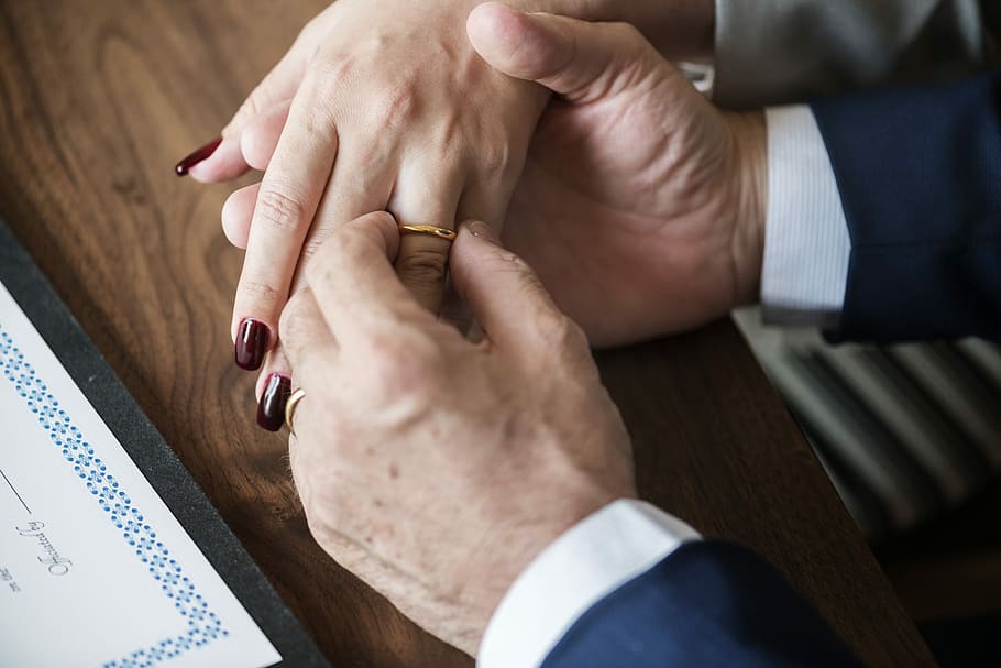 person putting gold-colored wedding band on woman's hand, adult