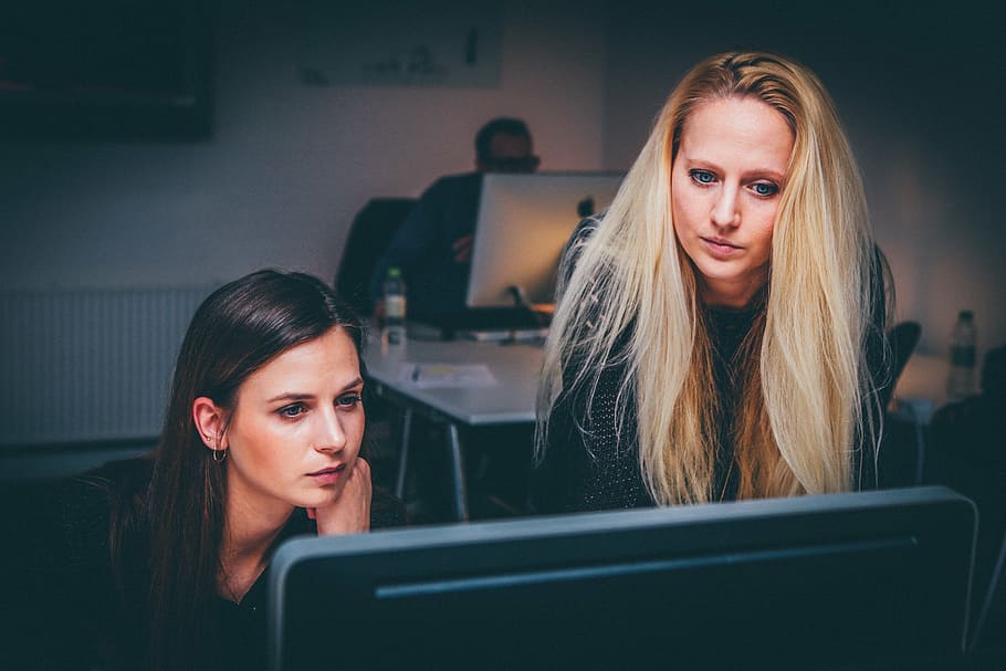 two women staring in black monitor in dim-lighted room, teamwork HD wallpaper