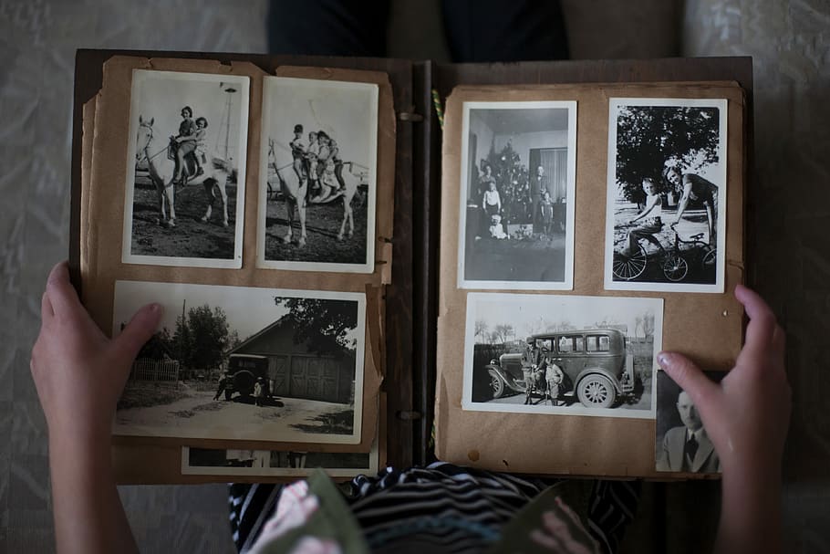 person opening photo album displaying grayscale photos, person holding photo album