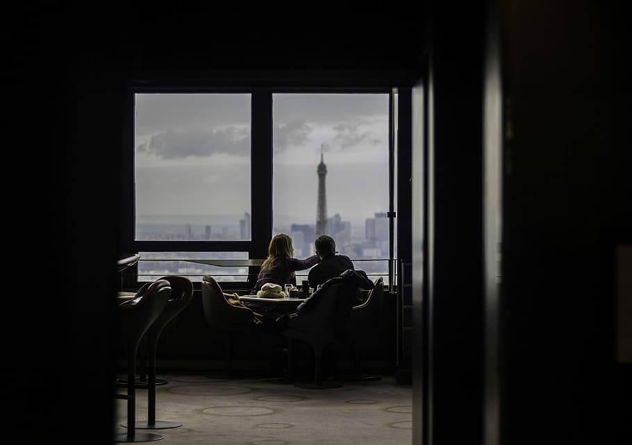 couple sitting while eating, man and woman facing tower while sitting in front of window HD wallpaper