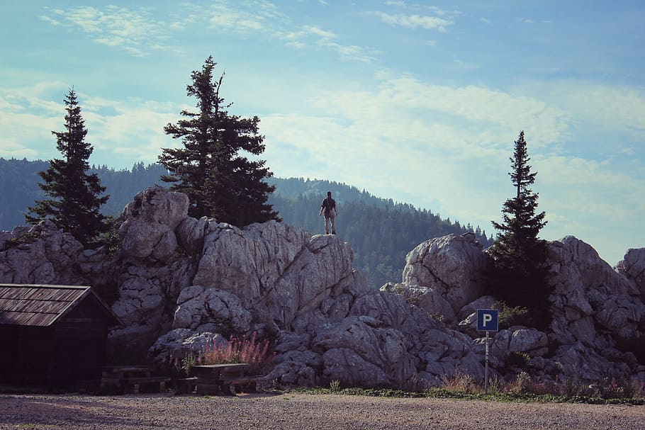 person standing on grey rock under blue sky, mountains, hiking HD wallpaper