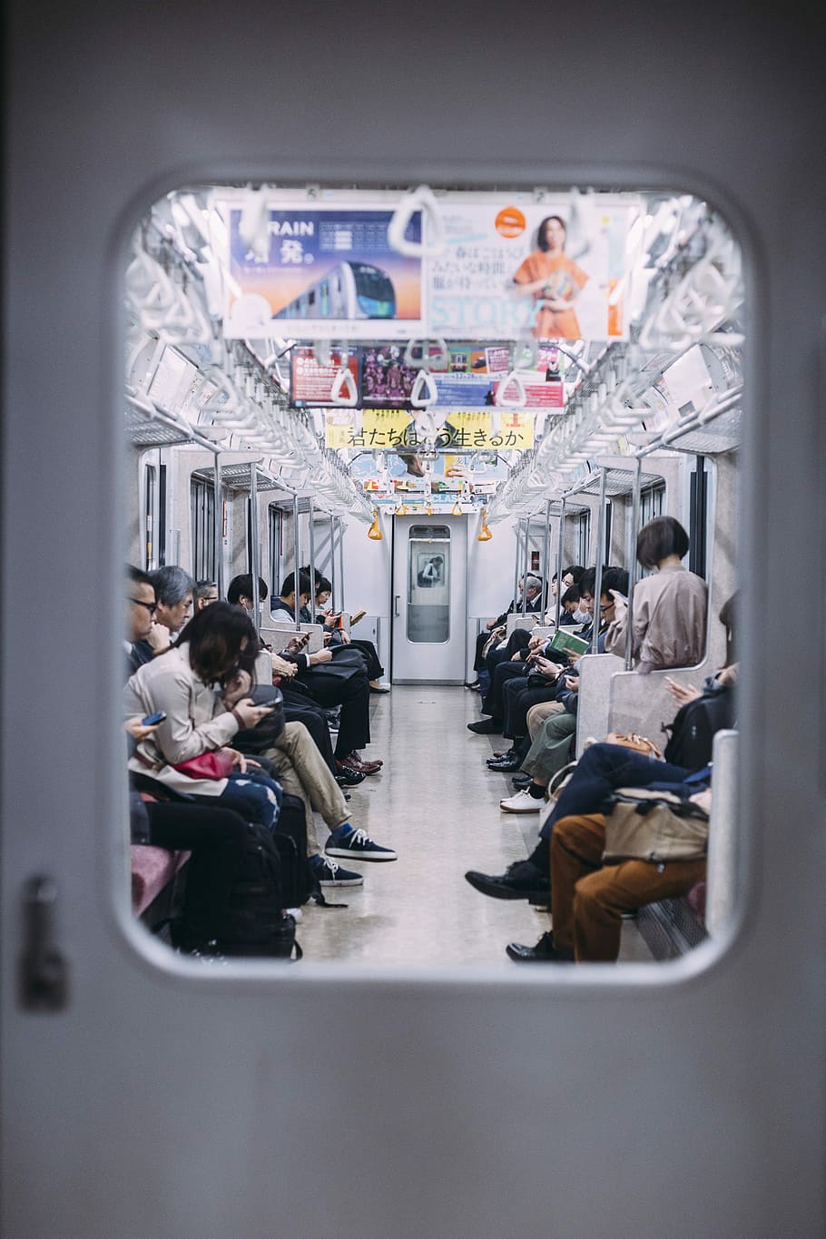 people at the train looking at their phones, photo of people sitting inside of train