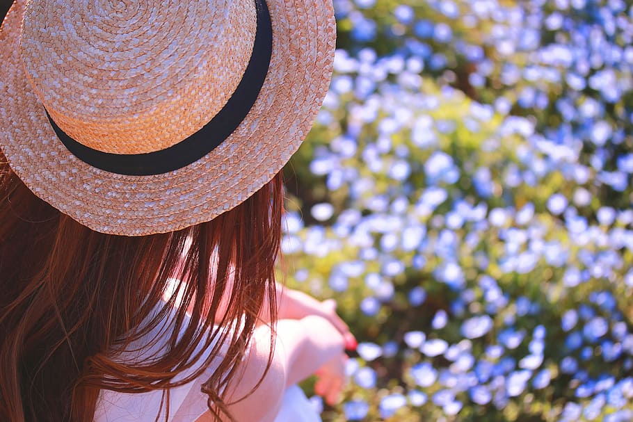 woman wearing white dress and sun hat with red long straight hair standing on top of blue flower field HD wallpaper