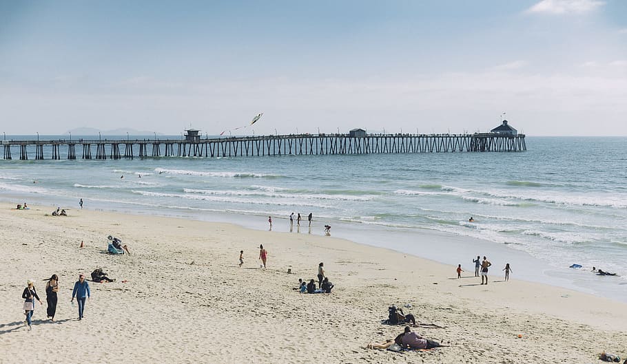 people at the beach swimming during daytime, group of people playing on white sand seashore during daytime HD wallpaper