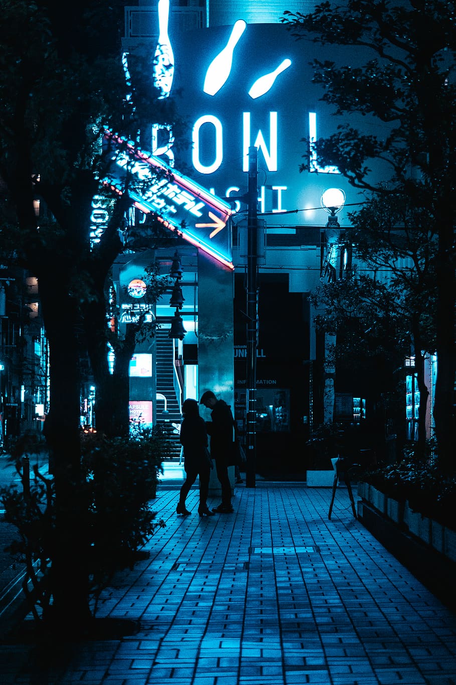man and woman standing in front of bowl building, urban, neon light