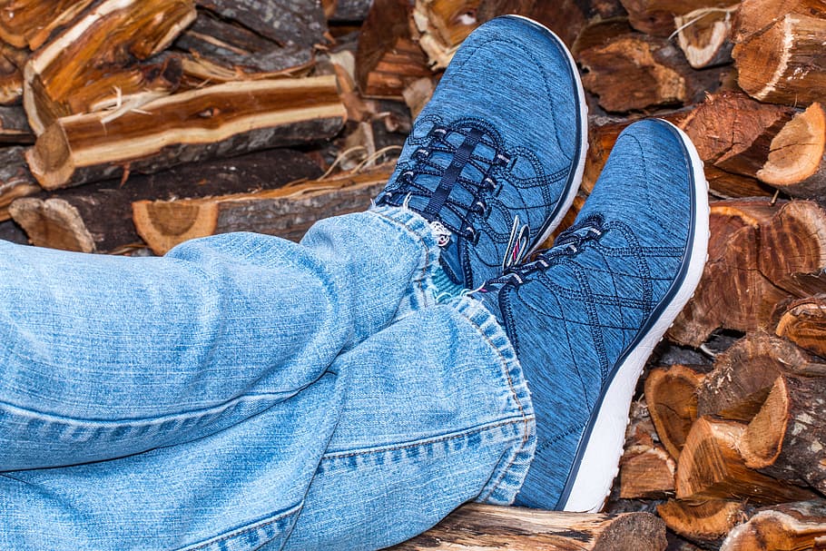 person in blue low-top sneakers leaning on fire woods, shoes