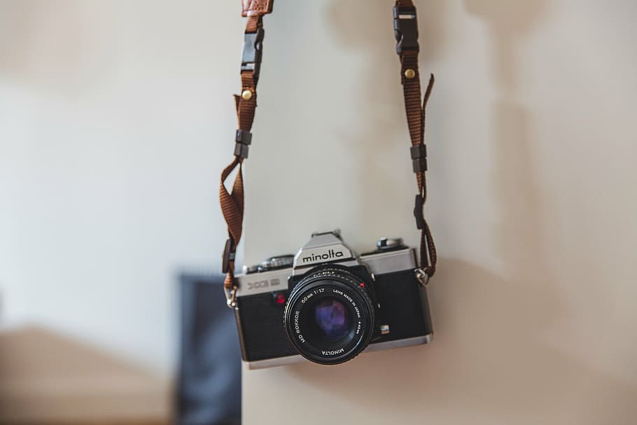 black and gray camera hanging on white wall, silver, dslr, strap