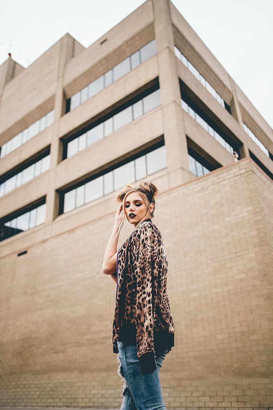 woman with hand on hair standing in front of brown wall, woman standing in front of building at during daytime HD wallpaper