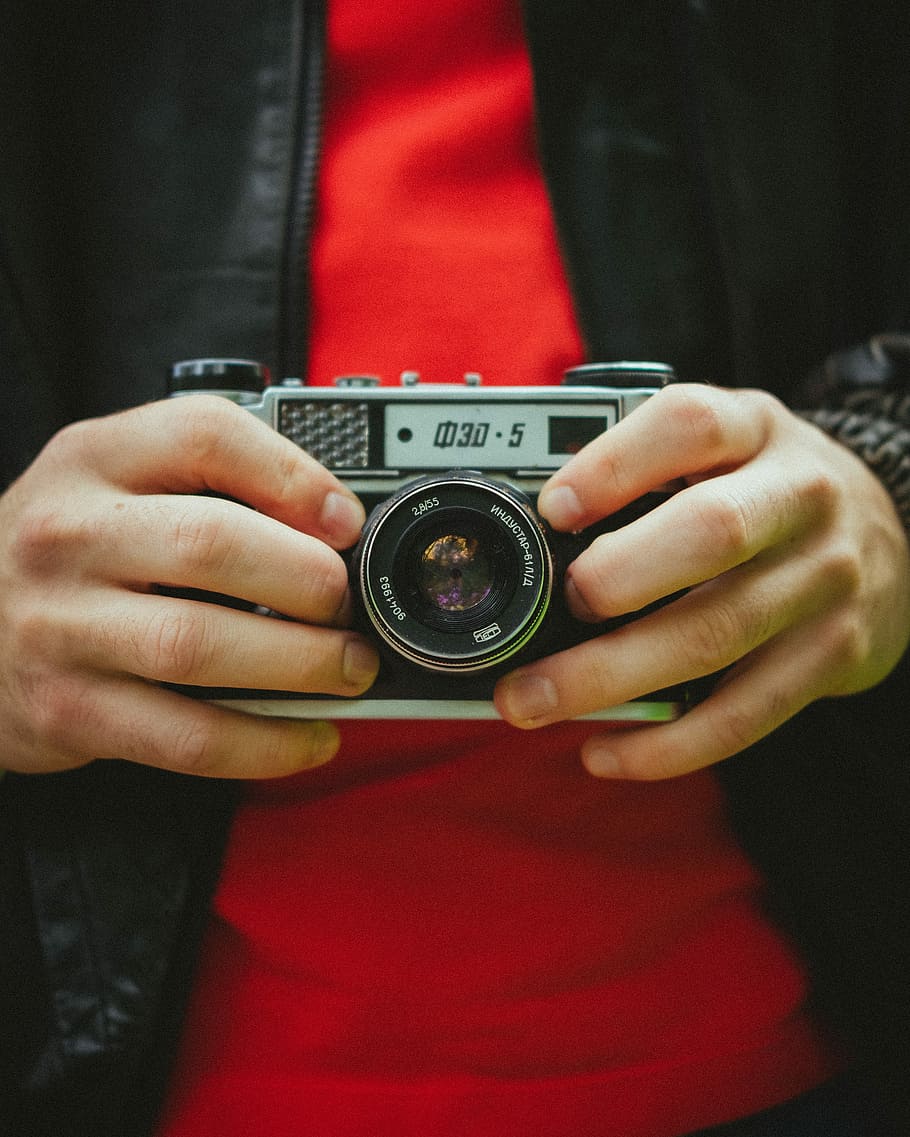 person holding gray and black camera, shallow focus photo of person holding gray SLR camera HD wallpaper