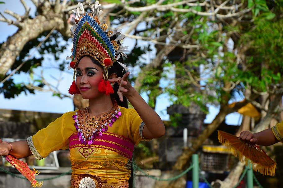 woman wearing yellow and pink traditional dress dancing under brown tree