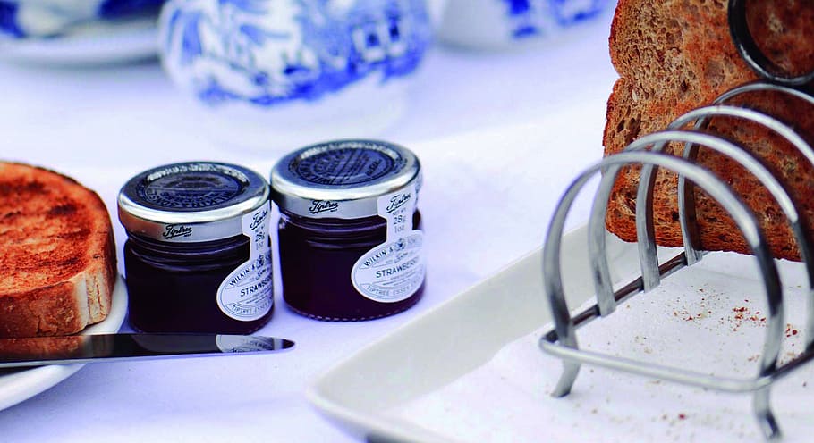 two glass jars near toasted bread, two purple cream jars on white table HD wallpaper