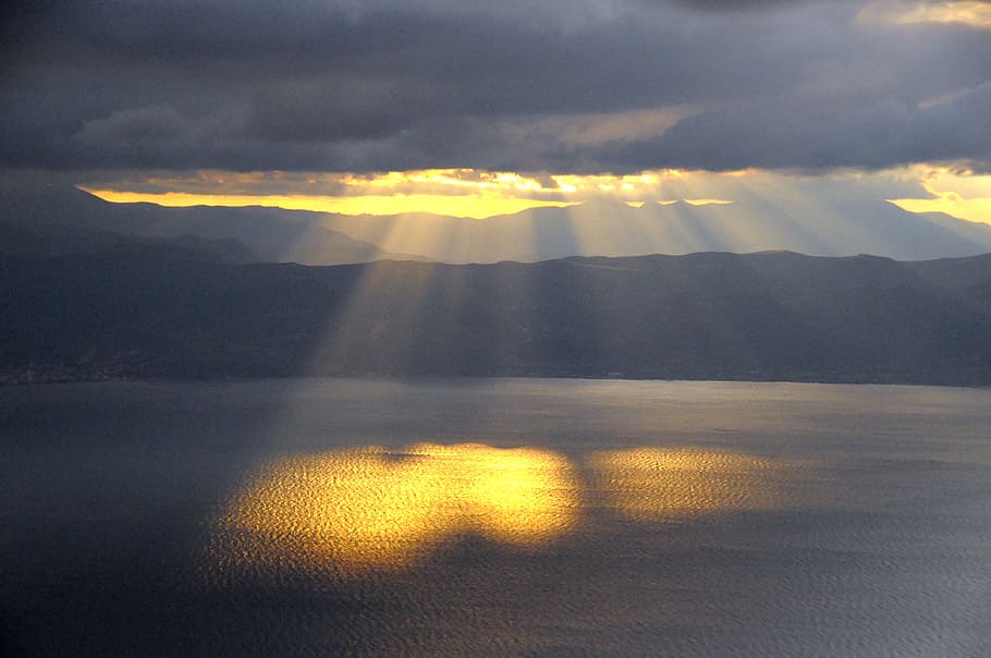 sun rays on body of water during dark clouds, setting sun, heaven, HD wallpaper