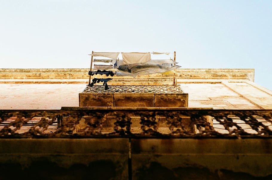 worm's-eye view of balcony with laundry hangings, brown concrete building HD wallpaper