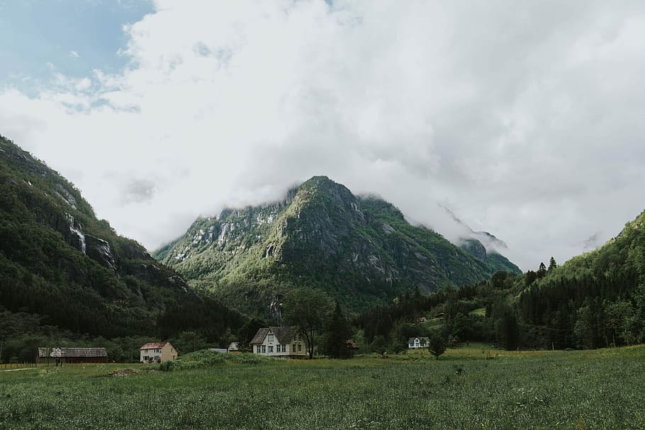 green mountains under cloudy sky, several houses near mountain during daytime HD wallpaper