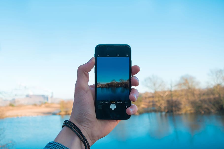 person showing photo of body of water, person taking photo of lake HD wallpaper