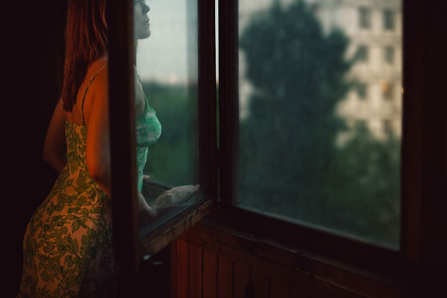 She is looking the window. The girl sitting on the balcony HD. Redhead balcony leaning forward. Broken Window photo.