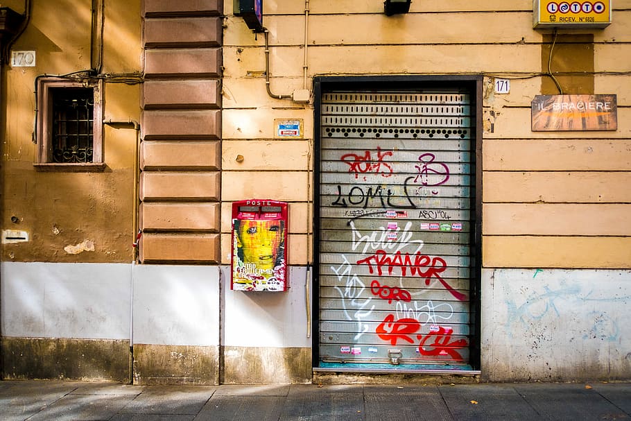 vandalized roller shutter door, closed gray roll-top gate, wall