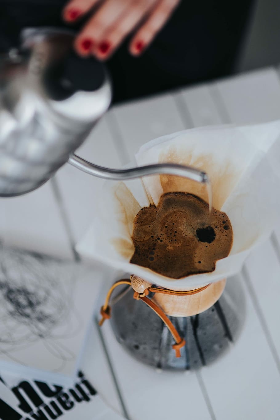 Woman pouring water in Chemex filter coffee maker, cafe, hot water