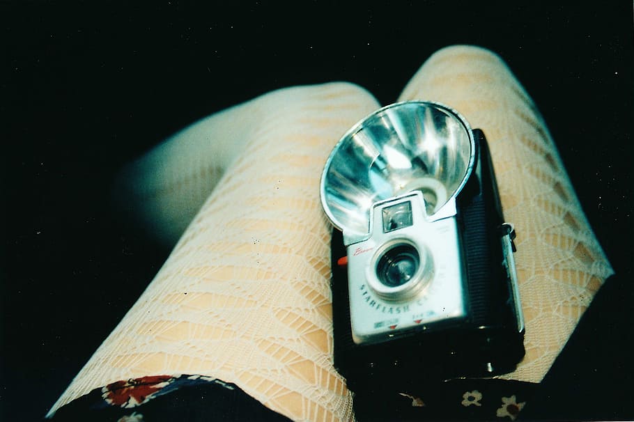 vintage gray and black camera with flash on orange fabric cloth, black and gray camera on person's lap HD wallpaper