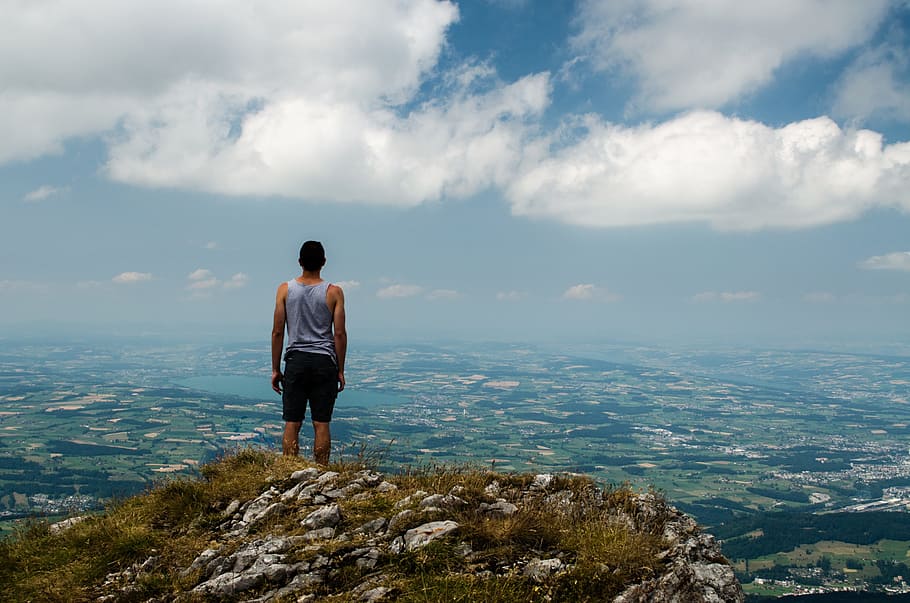 man wearing gray tank top standing in front of cliff during daytime HD wallpaper