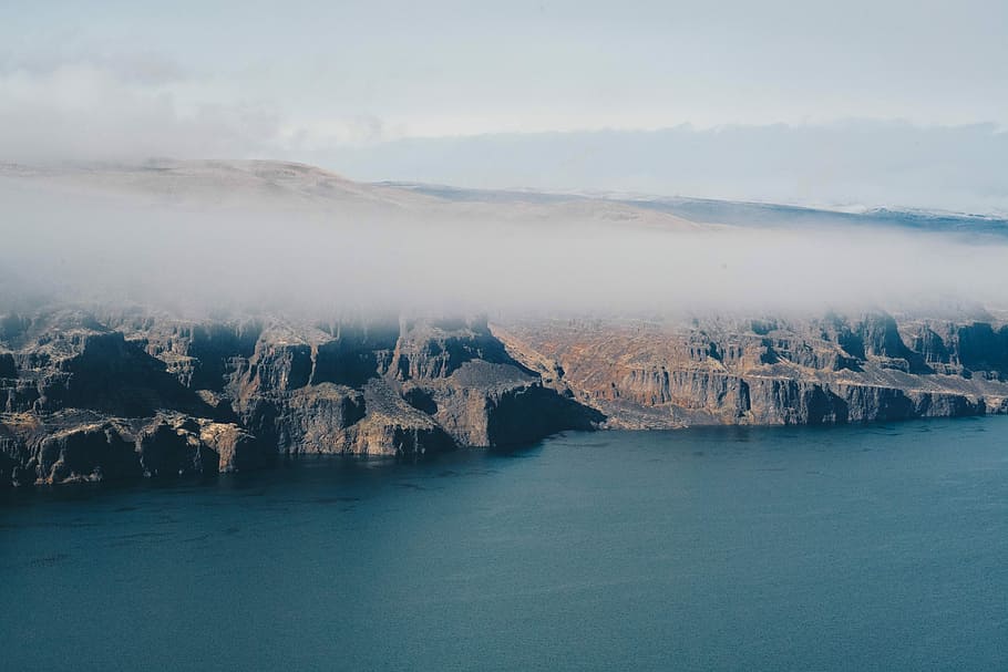 landscape photo of cliff, aerial photography of body of water beside mountains during daytime HD wallpaper
