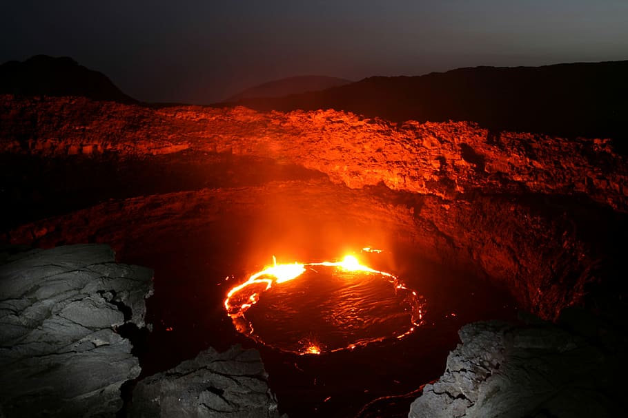 body of water with red flame, red flame on body of water near cliff during night time