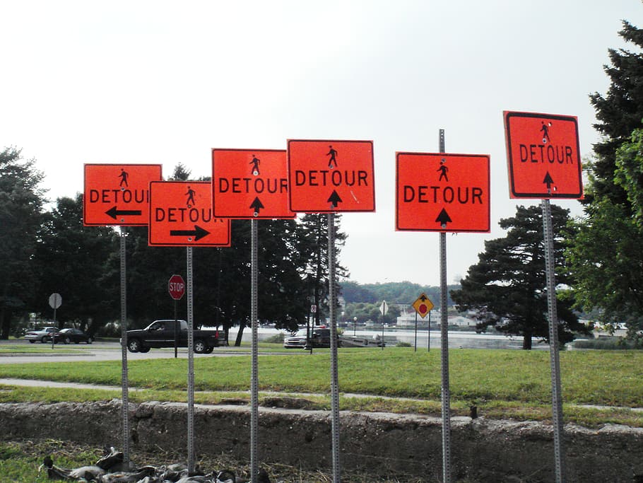 Detour road signage's near green field under white skies, confusion