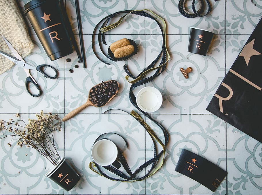brown and black straps near coffee beans and cups on gray tiles, coffee beans with cups on ceramic tile floor HD wallpaper